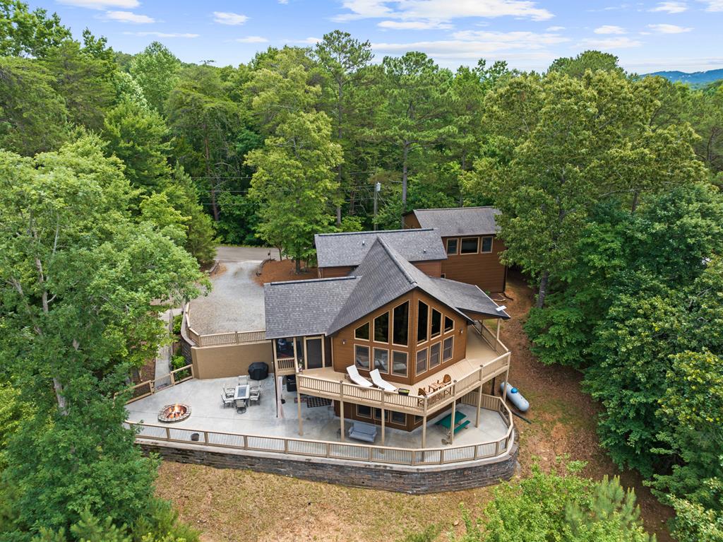 Single-story blue ranch-style house with a long white-railed front porch, set in a grassy yard with trees and distant hills on a clear day.